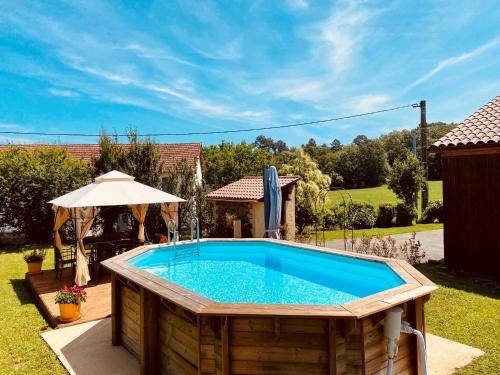a swimming pool in a yard with an umbrella at 3-Bedroom Holiday Home with Aircon and Private heated plunge Pool - 5 Minutes from Monpazier in Capdrot