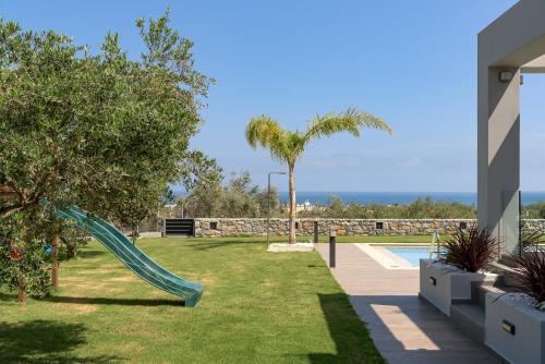 a slide in a yard next to a swimming pool at Agrielia Villas, featuring Heated Spa Whirlpool, By ThinkVilla in Pigianos Kampos
