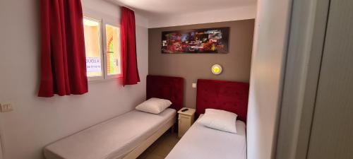 Cette petite chambre comprend 2 lits et des rideaux rouges. dans l'établissement Vacances inoubliables en Ardèche 4 personnes, à Grospierres