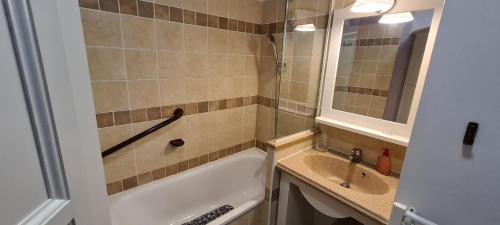 une salle de bain avec une baignoire, un lavabo et un miroir dans l'établissement Vacances inoubliables en Ardèche 4 personnes, à Grospierres