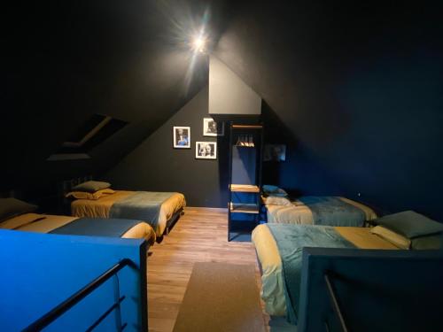a room with three beds in a dark room at PADDOCK 24 Arnage - Loft Le Mans in Arnage