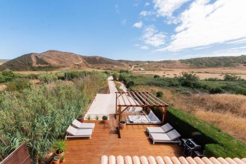 a wooden deck with white lounge chairs in the desert at Casa da Almargens in Bordeira