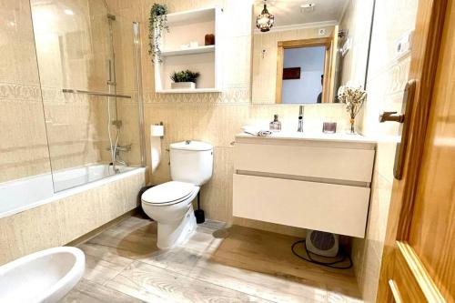 uma casa de banho com um WC, um lavatório e uma banheira em 12-Apartamento en la playa Piscina em Alicante