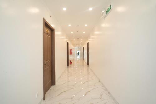 a hallway with white walls and white floors and a long corridor at BinBin Phúc Dalat Hotel in Da Lat