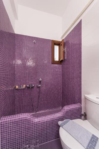 a purple tiled bathroom with a shower and a toilet at Villa Voula in Perissa