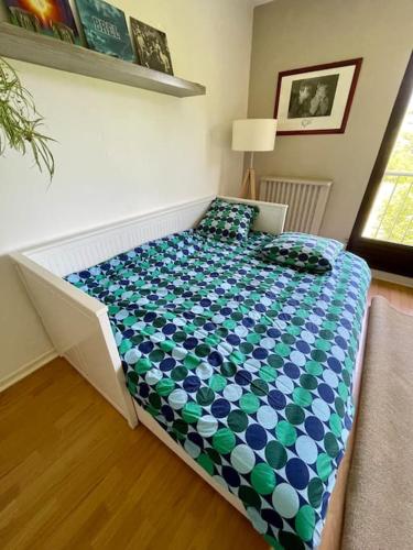 a bedroom with a bed with a blue and green comforter at Studio au pied du Vercors in Saint-Jean-en-Royans