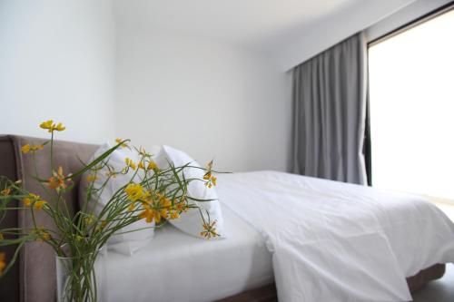 a vase filled with flowers sitting next to a bed at Swiss Rivage Hotel in Vlorë