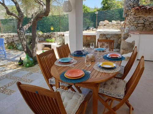 una mesa de madera con platos y copas de vino. en Villa Cugnana ( alle porte della Costa Smeralda ), en Cugnana