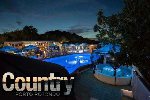 una gran piscina con sombrillas azules y un complejo en Villa Cugnana ( alle porte della Costa Smeralda ), en Cugnana