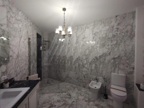 a bathroom with a sink and a toilet and a chandelier at Il Giardino della Scuncerta in Lecce