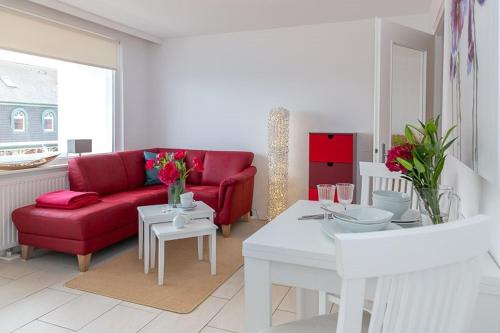 een woonkamer met een rode bank en een tafel bij Duen12_36 in Westerland