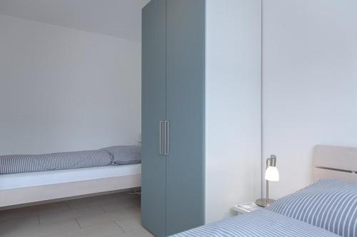 een slaapkamer met een bed en een blauwe kast bij Duen12_36 in Westerland