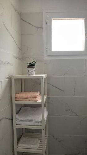 a bathroom with a shelf with towels and a window at Joli studio dans le village in Saintes-Maries-de-la-Mer