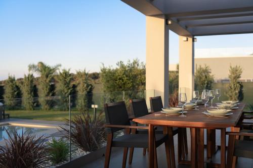 a wooden table and chairs on a patio at Agrielia Villas, featuring Heated Spa Whirlpool, By ThinkVilla in Pigianos Kampos
