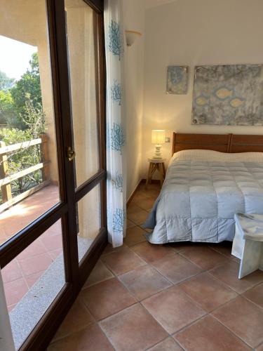 a bedroom with a bed and a door to a balcony at Costa Paradiso House in Li Valcaggi