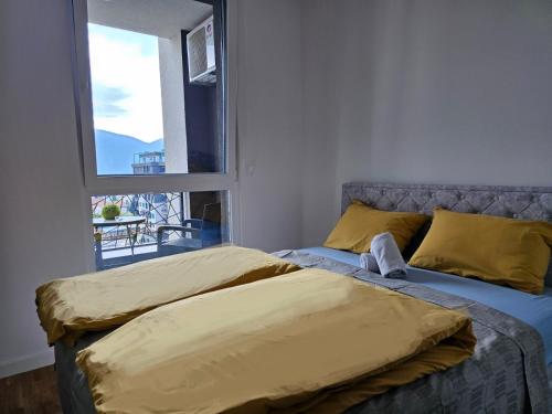 Una cama con almohadas amarillas y una ventana en una habitación. en Apartment Bulevar Square, en Sarajevo