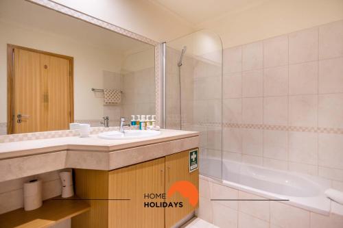 a bathroom with a sink and a tub and a mirror at #107 T1 Vista das Ondas by Home Holidays in Olhos de Água