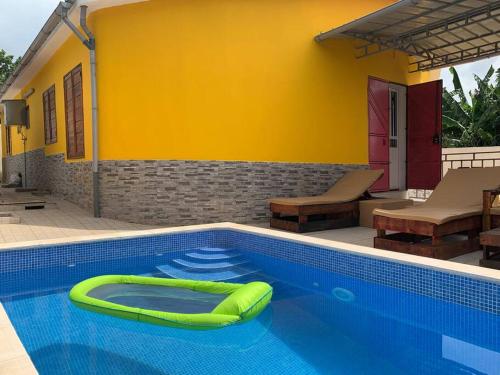 a swimming pool with a green inflatable raft in it at Ubá Budo Praia - Villa in São Tomé