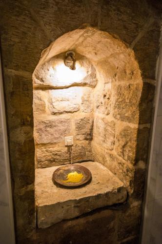 a stone bathroom with a sink in a stone wall at The Burrow Guest House in Tarxien