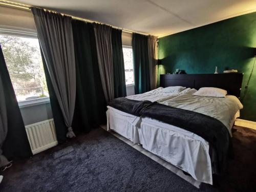 um quarto com uma cama grande e uma parede verde em Sällskapshus i mysig skärgårdsmiljö em Ramsdalen