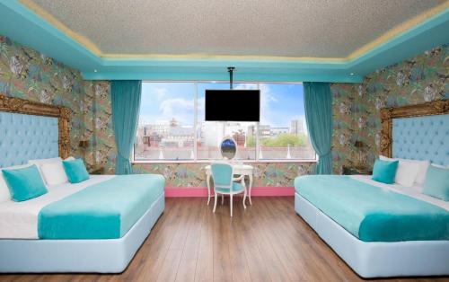 a bedroom with two beds and a table and a tv at The Shankly Hotel in Liverpool