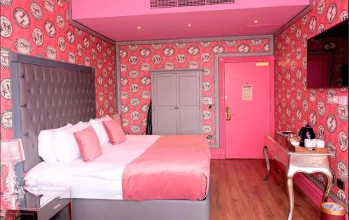 a bedroom with a large bed with pink walls at The Shankly Hotel in Liverpool