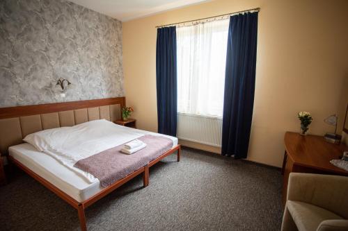 a bedroom with a bed and a window with blue curtains at Hotel pod Wierzba in Świdnica
