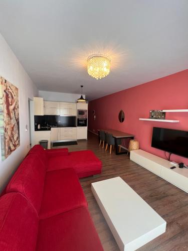 Hard Rock Apartments في سارنده: غرفة معيشة مع أريكة حمراء وطاولة