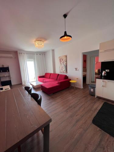 Hard Rock Apartments في سارنده: غرفة معيشة مع أريكة حمراء وطاولة