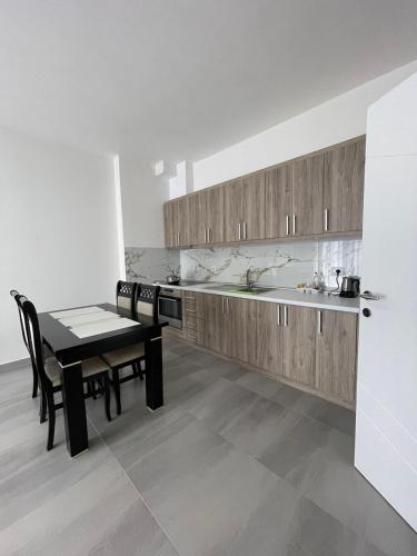 een keuken met houten kasten en een tafel en stoelen bij Jurgen's Apartaments in Vlorë