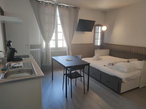 une chambre avec un lit, une table et un lavabo dans l'établissement *LES STUDIOS L'AMANDINE*, à Périgueux