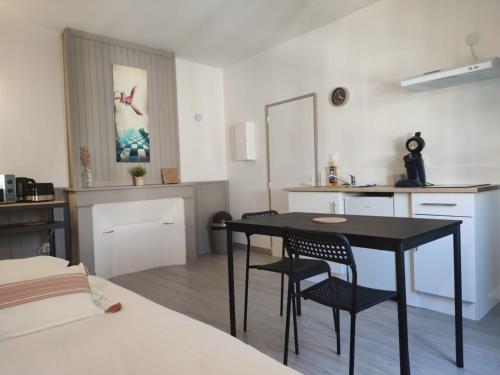 Il comprend une chambre avec une table et des chaises ainsi qu'une cuisine. dans l'établissement *LES STUDIOS L'AMANDINE*, à Périgueux