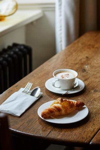 a table with a cup of coffee and a croissant at Victorian House in Grasmere