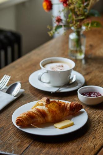 a croissant and a cup of coffee on a wooden table at Victorian House in Grasmere