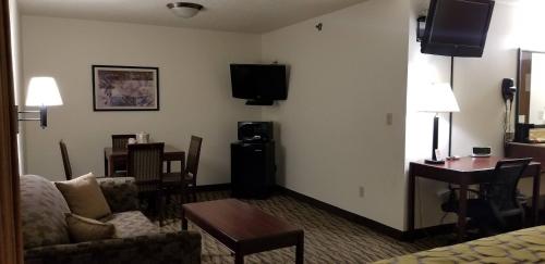 a hotel room with a couch and a table and a desk at Baymont by Wyndham Harlan in Harlan