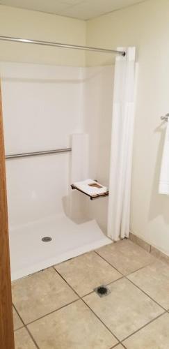 a glass shower in a room with a tile floor at Baymont by Wyndham Harlan in Harlan