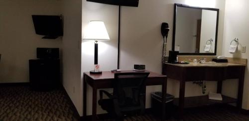 a hotel room with a desk with a lamp and a mirror at Baymont by Wyndham Harlan in Harlan
