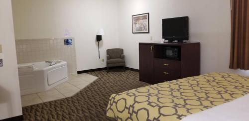 a hotel room with a bed and a tub and a tv at Baymont by Wyndham Harlan in Harlan