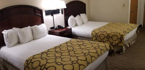 a hotel room with two beds with white and yellow sheets at Baymont by Wyndham Harlan in Harlan