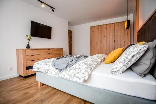a bedroom with a bed with pillows and a television at Podtatrzańskie Apartamenty in Nowy Targ