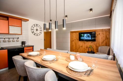 a kitchen and dining room with a wooden table and chairs at Podtatrzańskie Apartamenty in Nowy Targ