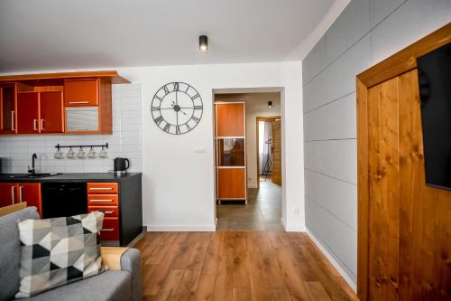 a kitchen and living room with a clock on the wall at Podtatrzańskie Apartamenty in Nowy Targ