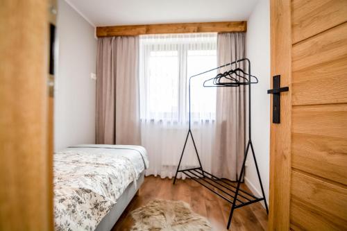 a room with a bed and a tripod in front of a window at Podtatrzańskie Apartamenty in Nowy Targ