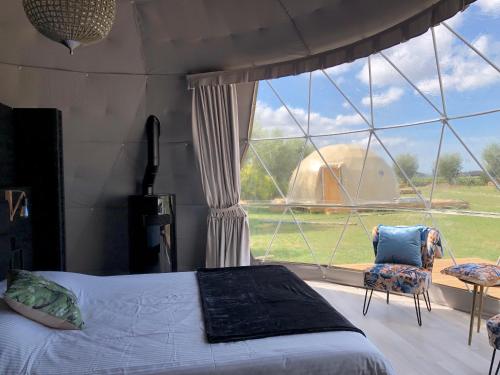 a bedroom with a bed and a large window at ID Glamping De Coude Scheure in Middelkerke