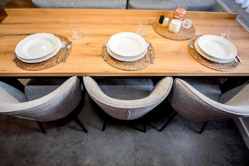a wooden table with chairs and white plates and glasses at Podtatrzańskie Apartamenty in Nowy Targ