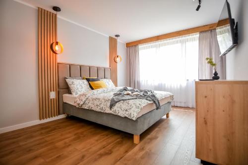 a bedroom with a bed and a large window at Podtatrzańskie Apartamenty in Nowy Targ