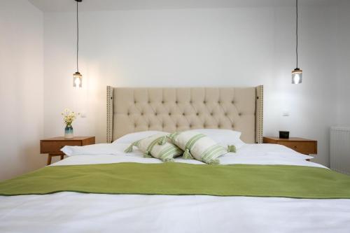 a bedroom with a large white bed with two green pillows at Chalet Bora in Vişeu de Jos