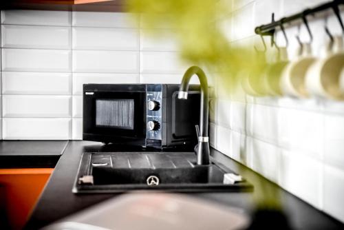 a kitchen counter with a sink and a microwave at Podtatrzańskie Apartamenty in Nowy Targ