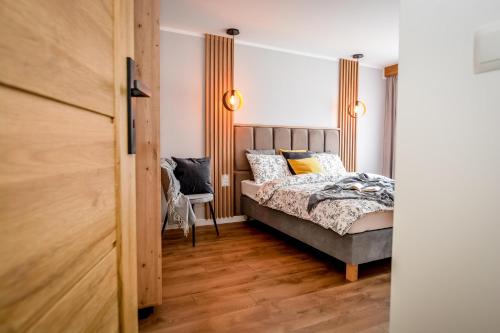 a bedroom with a bed and a chair at Podtatrzańskie Apartamenty in Nowy Targ