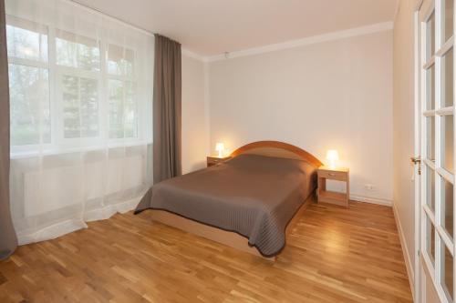 1 dormitorio con cama, ventana y suelo de madera en Vytauto apartamentai, en Palanga